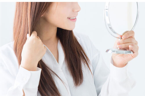 鏡で髪を見て笑顔になる女性