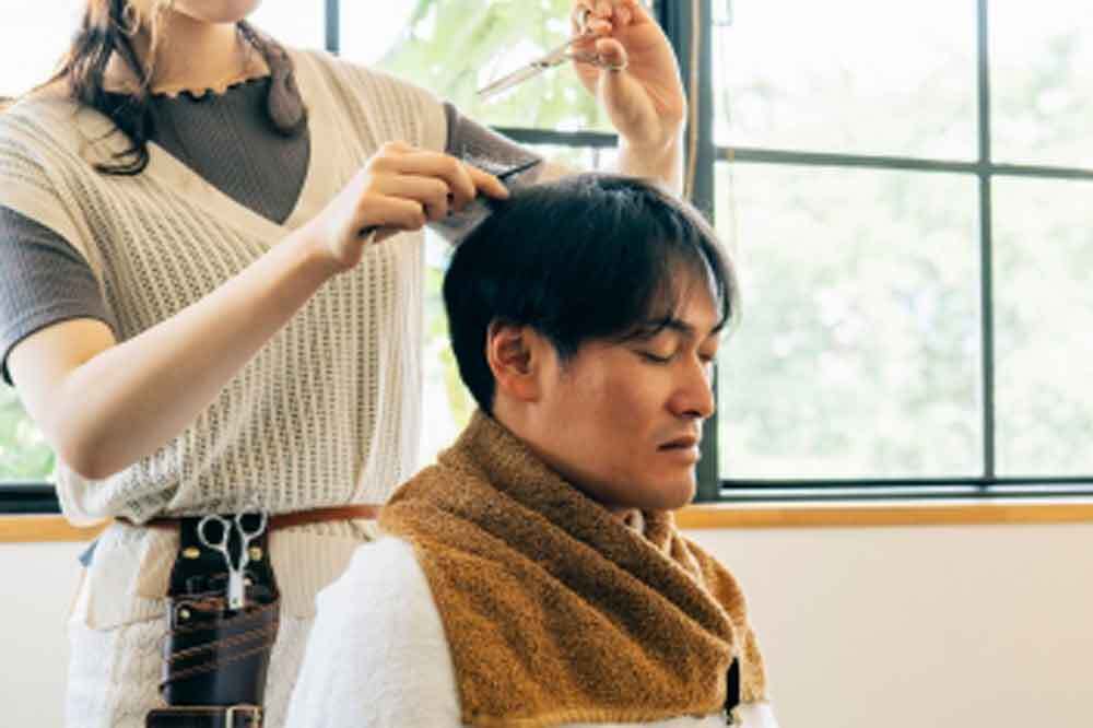 目をつむってカットしてもらう男性