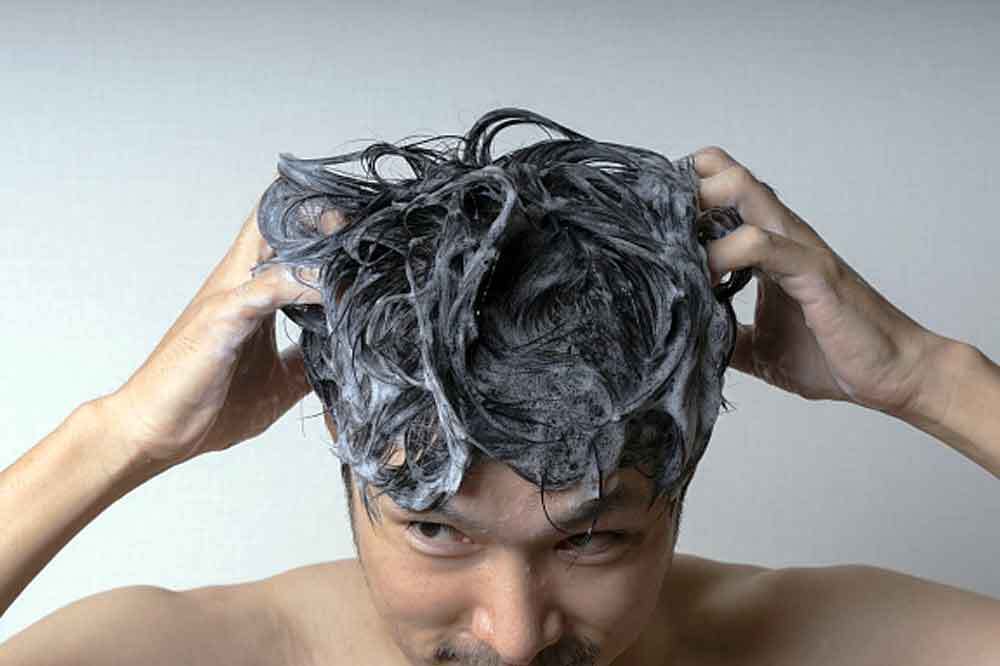 炭酸シャンプーで髪を洗う男性