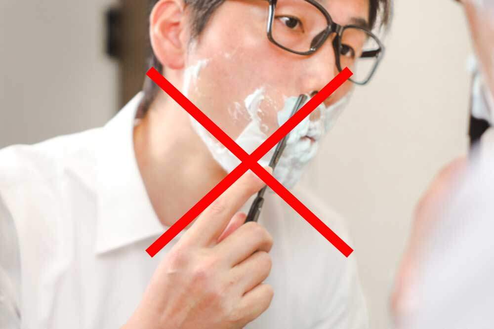 鼻の下のヒゲを剃る男性