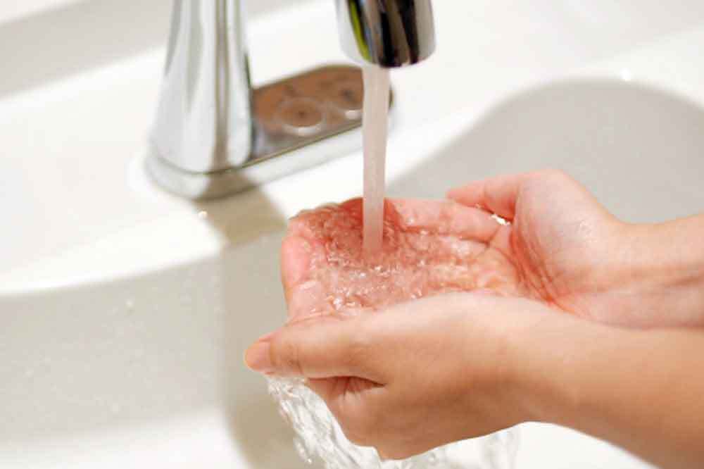 手に水をためて顔を洗う