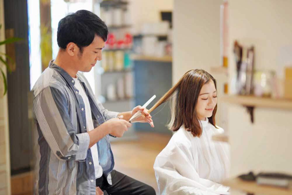 女性の髪をカットする男性美容師