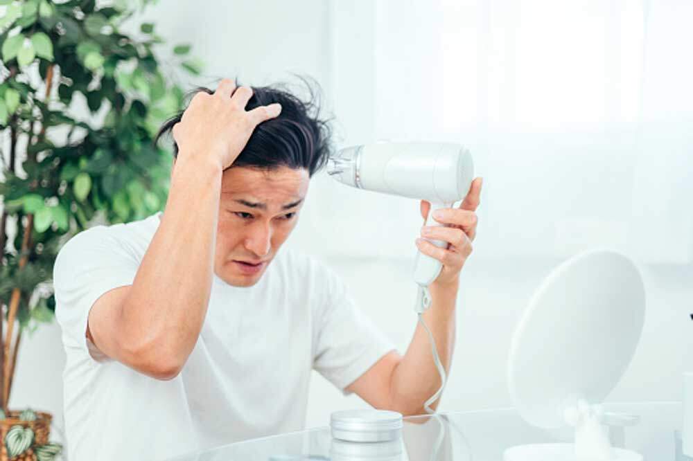 ドライヤーで髪を乾かす男性
