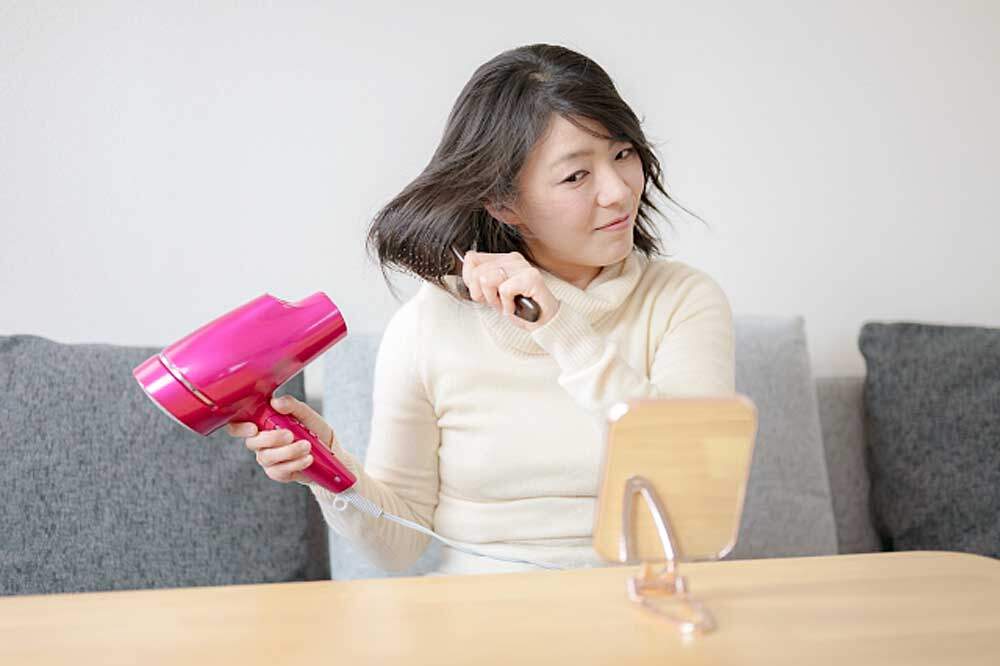 ドライヤーでくせ毛を伸ばす女性