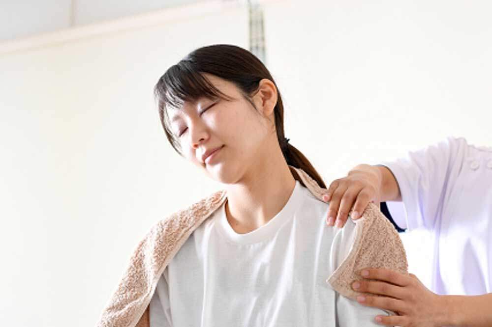 肩をマッサージしてもらう女性